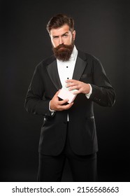 Serious Man In Tuxedo Bow Tie Formalwear On Black Background With Gift Box. Boxing Day