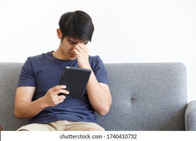 Serious man using tablet while sitting on Sofa. COPY SPACE. Trading. WORK FROM HOME WFH Concept.