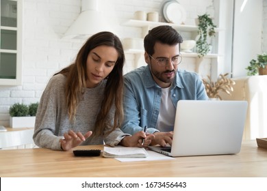 Serious man and woman calculating bills, using calculator and laptop, online banking services, family discussing and planning budget, focused wife and husband checking finances together - Shutterstock ID 1673456443