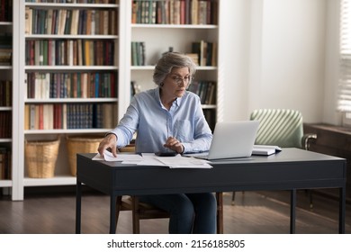 Serious Mature Business Lady Doing Financial Accounting Paperwork At Office Workplace, Checking Paper Bills, Using Banking App On Laptop, Calculating Budget, Expenses