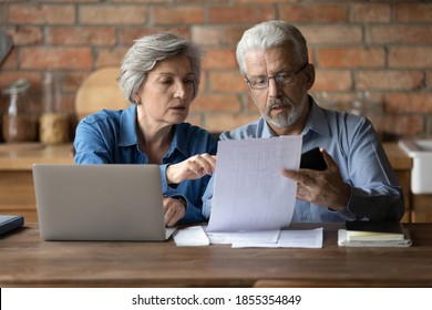 Serious Mature Couple Checking Financial Documents, Domestic Bills, Planning Budget Together, Sitting At Desk With Laptop, Senior Man And Woman Counting Taxes, Discussing Bank Debt Or Loan Payment