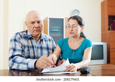 Serious Mature Couple Fills In Questionnaire  At Table