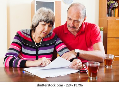 Serious Mature Couple Reading Financial Document