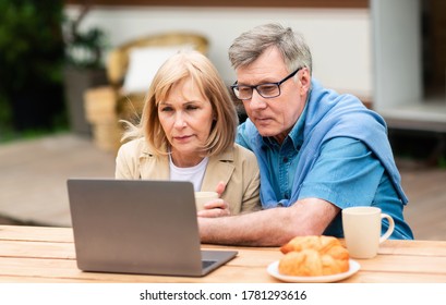 Serious Mature Couple Using Laptop Computer Near Camper Van Outside, Panorama