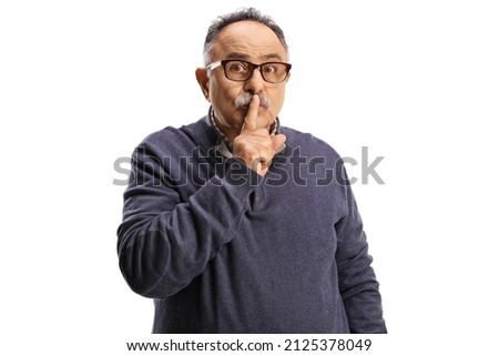 Serious mature man gesturing silence with finger over mouth isolated on white background
