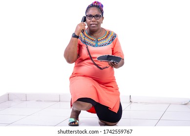 Serious Mature Woman Kneeling On The Floor And Talking On The Mobile Phone.