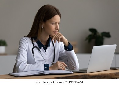 Serious medic professional, doctor, physician using laptop, giving online virtual consultation, making video call to patient, reading electronic medical records. Telemedicine, remote appointment