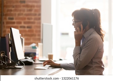 Serious middle aged businesswoman sit at office desk talking on phone looking at computer, female manager secretary making call contacting client consulting customer by mobile working on pc online - Powered by Shutterstock