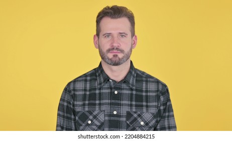 Serious Middle Aged Man Looking At The Camera, Yellow Background