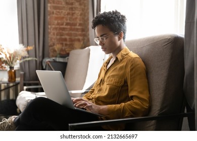 Serious millennial African student, homeowner woman, freelance employee working at laptop in armchair, using online app, virtual service, for studying, payment, browsing Internet - Shutterstock ID 2132665697