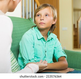 Serious  Mother And  Teen Boy Talking In Home Interior. Focus On Son