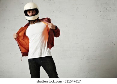 Serious motorcyclist showing the orange lining of his burgundy air jacket wearing vintage helmet isolated on white