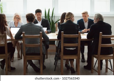 Serious Multi-ethnic Business People Team Sitting At Conference Table, Senior Executives Working Together With Young Managers At Office Staff Meeting, Focused Group Negotiations Or Teamwork Concept