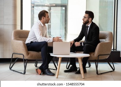 Serious multiethnic male business partners talk discussing potential cooperation or shared project, concentrated successful international businessmen speak brainstorm at meeting or briefing in office - Shutterstock ID 1548555704