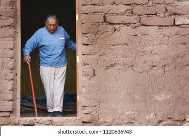 Serious Native American Old Man With Walking Stick Leaving His House In The Countryside. 