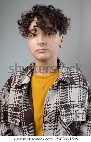Serious non-binary man smiling at the camera.