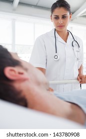 Serious Nurse Taking Care Of A Lying Patient In His Bed