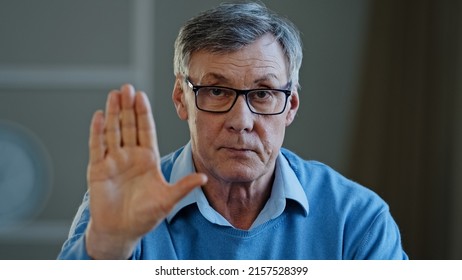 Serious Old Senior Mature 60s Man Stretch Out Palm To Camera Says Stop Gesture Indoors. Social Problems Older Generation Disrespect Ban Refusal Disagreement. Aged Businessman Trouble Denial Rejection