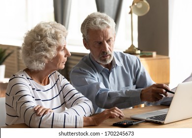 Serious Older Couple Using Laptop, Planning Budget, Checking Bills Together, Mature Woman Using Calculator, Senior Man Pointing At Computer Screen, Discussing Bank Debt Or Loan Payment