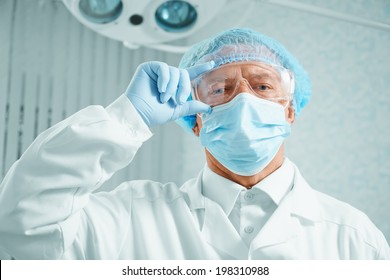 Serious older man surgeon in protective uniform in operating room - Powered by Shutterstock