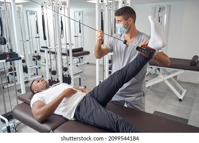 Serious Patient Doing Straight Leg Raise Using Gym Equipment