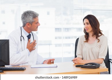 Serious Patient Talking With Her Doctor About Illness In Medical Office