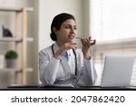 Serious pensive female Indian doctor recording audio message on smartphone, chatting with patient online, giving consultation, advice, explaining recommendation, treatment, using virtual voice app