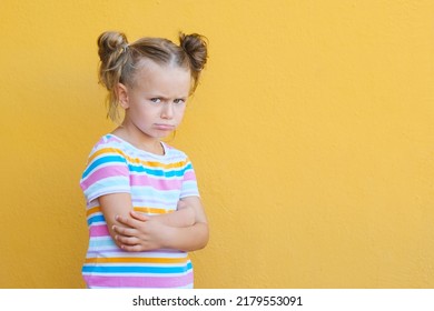 Serious Pensive Little Kid Girl Looking Unhappy At Camera, Upset Preschool Child Melancholic Or Bored, Isolated Over Yellow Studio Background