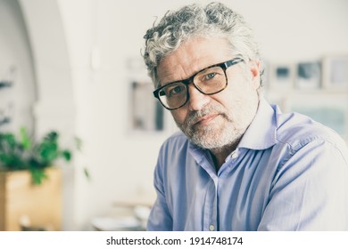 Serious Pensive Mature Business Man Wearing Shirt And Glasses, Sitting In Office Cafe, Looking At Camera. Medium Shot, Copy Space. Business Portrait Concept