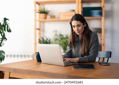 Serious pensive woman using laptop computer working from home office, communicating online, distantly working or studying for exam. - Powered by Shutterstock