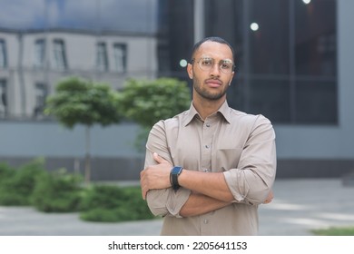 Serious And Pensive Young Office Worker With Crossed Arms Looking At Camera, Businessman In Shirt Outside Office Building Pensive