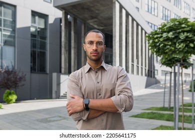 Serious And Pensive Young Office Worker With Crossed Arms Looking At Camera, Businessman In Shirt Outside Office Building Pensive