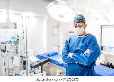 Serious Portrait Of Male Surgeon In Operating Room With Surgery Lights On And Medical Devices. Modern Hospital Details