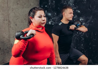 Serious Pretty Girl Holding The Weight And Working Out Indoors. Close Up Side View Photo. Determind Overweight Girl Doing Exercises In Fitness Center