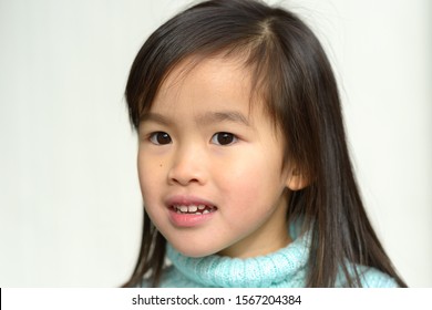 Serious Pretty Little Asian Girl In Blue Polo Neck Sweater In A Close Up Head Portrait