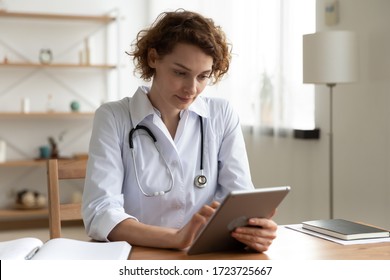 Serious professional doctor wearing white coat and stethoscope holding modern touchscreen gadget using digital tablet computer at work. Healthcare tech medical data network and telehealth concept. - Powered by Shutterstock