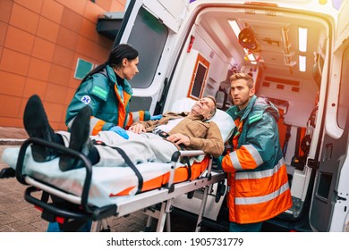 Serious and professional team of doctors in the ambulance moving on a patient into the hospital during an emergency situation.