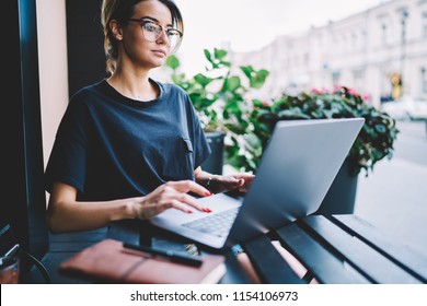 Serious puzzled young manager working on contemporary laptop in comfortable street cafe, thoughtful hipster girl searching information communicating during surfing social media network via netbook - Powered by Shutterstock