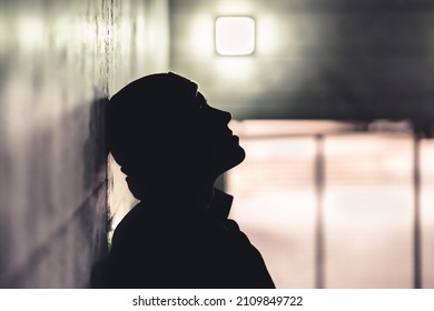 Serious Sad Man In Dark. Depressed Anxious Person Suffer From Trauma, Solitude Or Drug Addiction. Homeless Outcast With Shame After Mistake. Dramatic Moody Silhouette With Melancholy, Grief Or Sorrow.