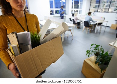 Serious Sad Woman In Sweater Carrying Cardboard Box Full Of Stuff And Leaving Office After Dismissal