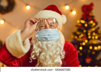 Serious Santa Claus In Medical Face Mask Warning About Danger Of Coronavirus Respiratory Infection And Calling People For Self-isolation At Home. Head Shot Of Father Christmas Having Online Video Chat