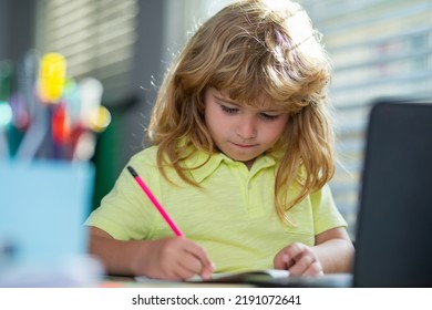 Serious School Child Writing Homework In School Class. Portrait Of School Kid Boy Siting On Table Doing Homework. Child Holding Pencil And Writing. Boy Drawing On White Paper At The Table.