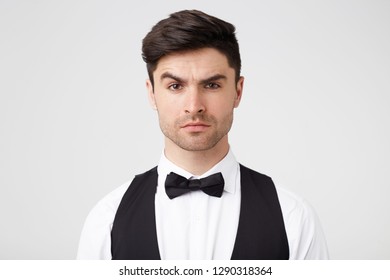 Serious self-confident attractive brunet with small stubble looks confidently, quizzically, incredulously, one eyebrow raised, smartly dressed, isolated over white background