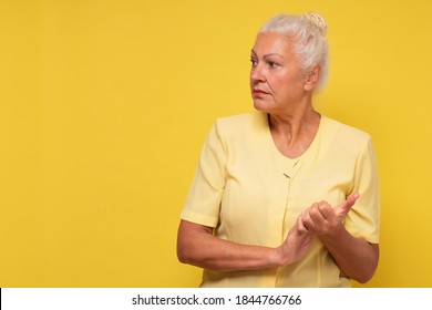 Serious Senior Hispanic Woman Looking Aside. Studio Shot On Yellow Wall.