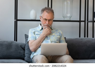 Serious Senior Man Using Online Virtual App On Laptop, Reading Notification, Message, Thinking Over Email, Making Decision. Mature Computer User Working From Home, Watching Webinar, Training