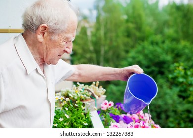 serious senior man watering the flowers on his balcony - Powered by Shutterstock