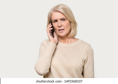 Serious senior mature woman isolated on grey studio background hold cellphone talking discussing problems, focused aged lady using smartphone, speak with wireless 5g connection, technology concept - Powered by Shutterstock