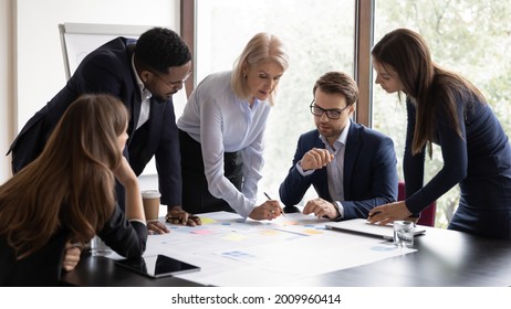 Serious senior mentor, corporate teacher training interns. Business coach, leader, boss teaching employees to analyze project documents, reviewing reports, using scrum method with sticky notes