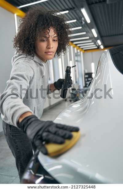 Serious\
service station worker waxing customer\
vehicle