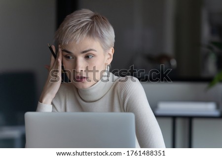 Serious short hired business woman sit in front of laptop considering decision she looking concerned. Thinking, deliberation process, employee searching solution having problem feels confused concept